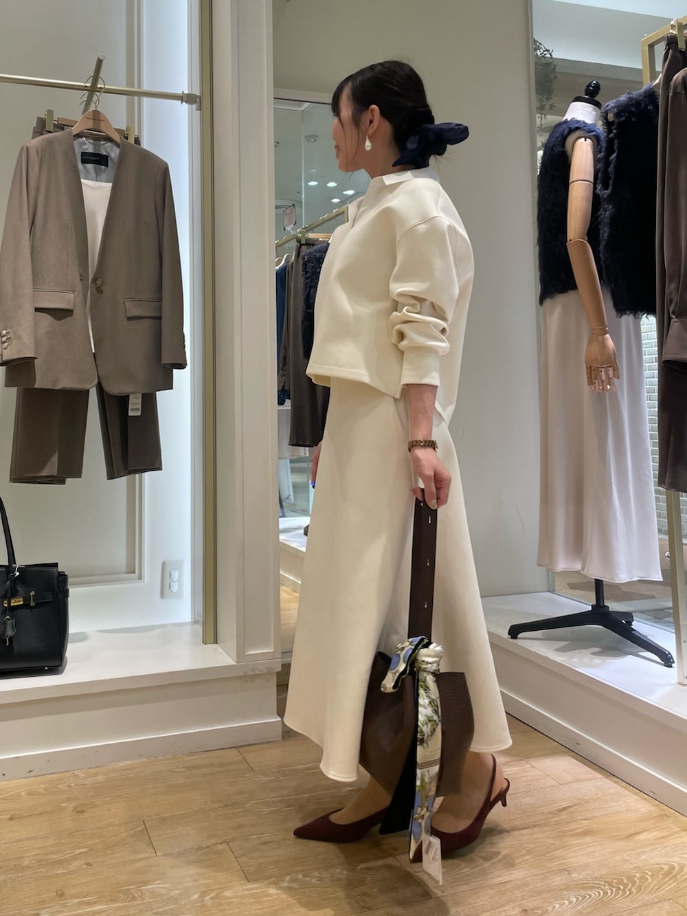 ブラウン系のショルダーバッグ、グリーン系のネクタイ、ホワイト系のTシャツ/カットソーを着用したレディースの秋コーディネートの2枚目の写真