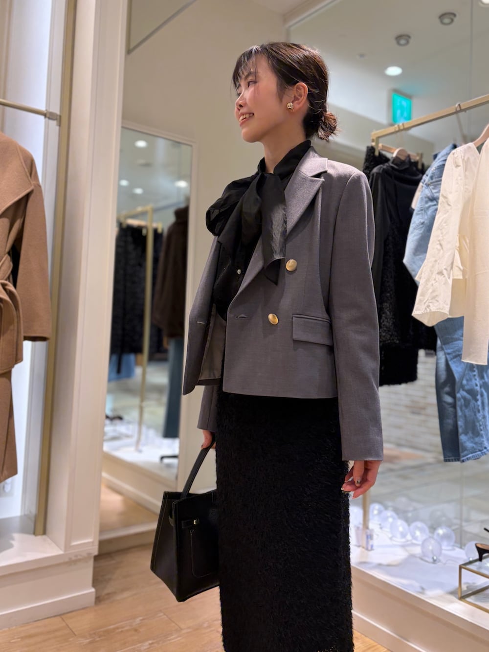 ブラック系のシャツ/ブラウス、グレー系のテーラードジャケット、ブラック系のスカートを着用したレディースの秋コーディネートの7枚目の写真
