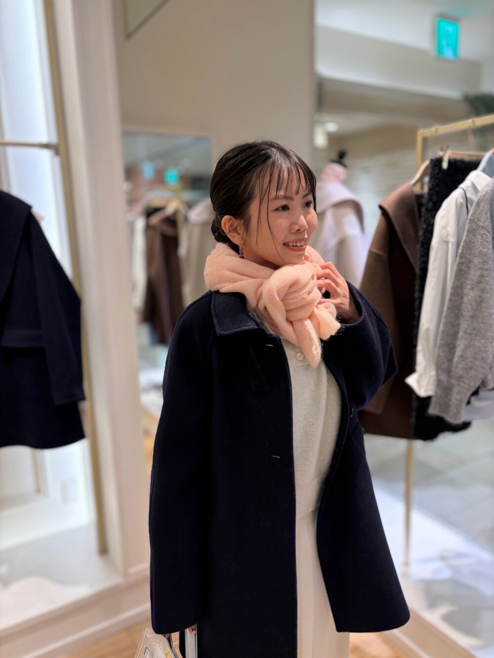 ホワイト系のニット/セーター、ホワイト系のスカート、ブルー系のステンカラーコートを着用したレディースの秋コーディネートの5枚目の写真