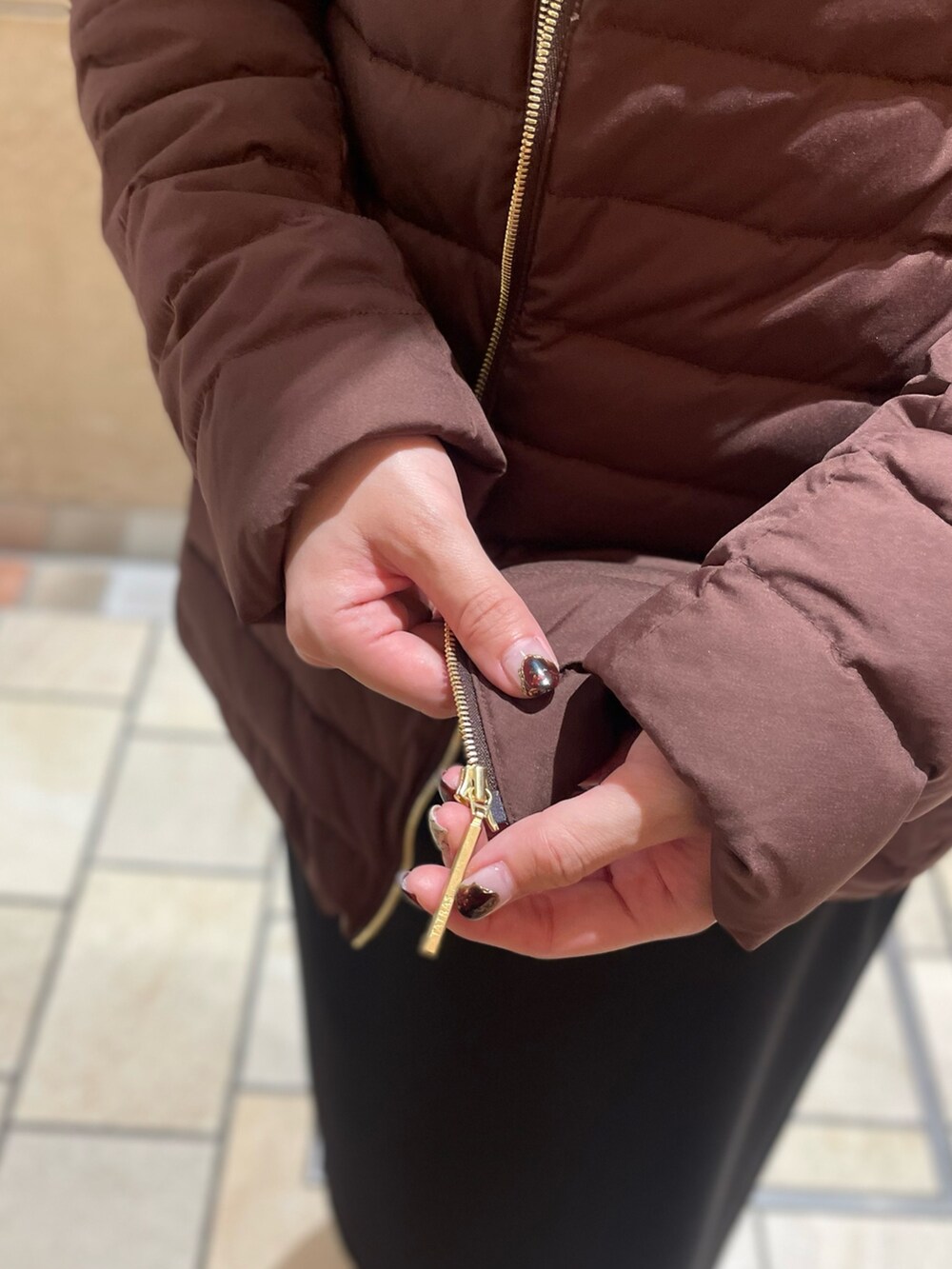 ブラウン系のダウンジャケット/コート、イエロー系のカーディガン/ボレロ、ブラック系のスカートを着用したレディースの秋コーディネートの6枚目の写真