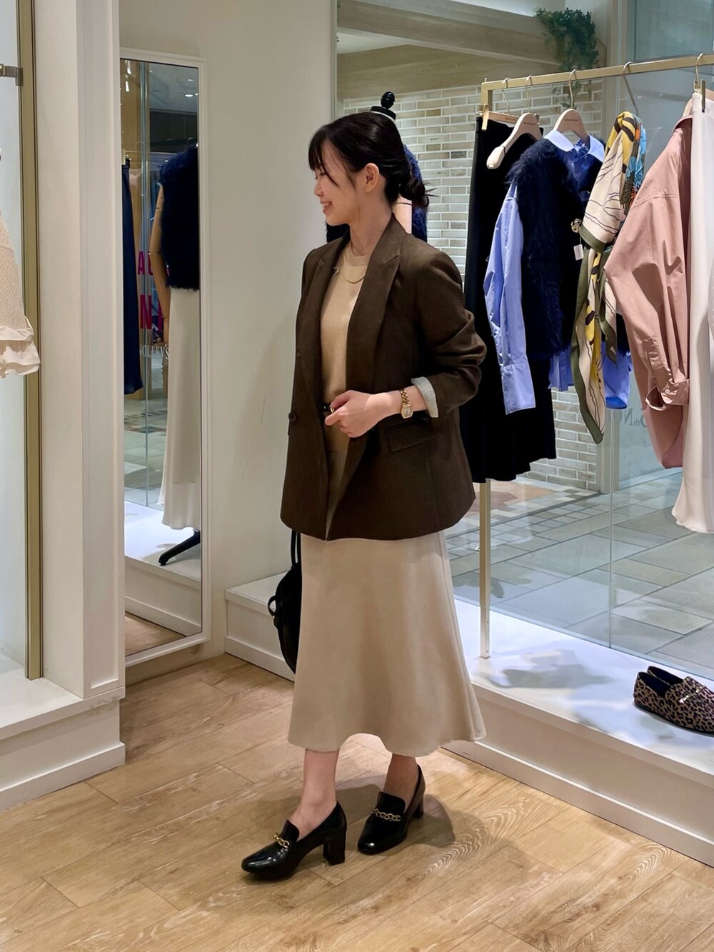 ブラウン系のテーラードジャケット、イエロー系のニット/セーター、ブラック系のショルダーバッグを着用したレディースの秋コーディネートの2枚目の写真