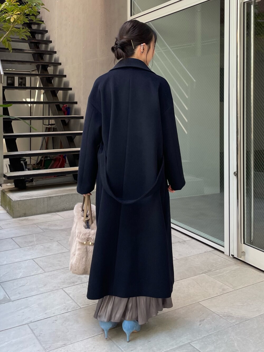 ブルー系のニット/セーター、ベージュ系のトートバッグ、グリーン系のスカートを着用したレディースの秋コーディネートの4枚目の写真