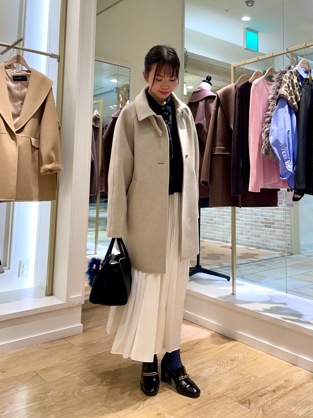 ベージュ系のステンカラーコート、ブルー系のシャツ/ブラウス、ブラック系のトートバッグを着用したレディースの秋コーディネートの8枚目の写真