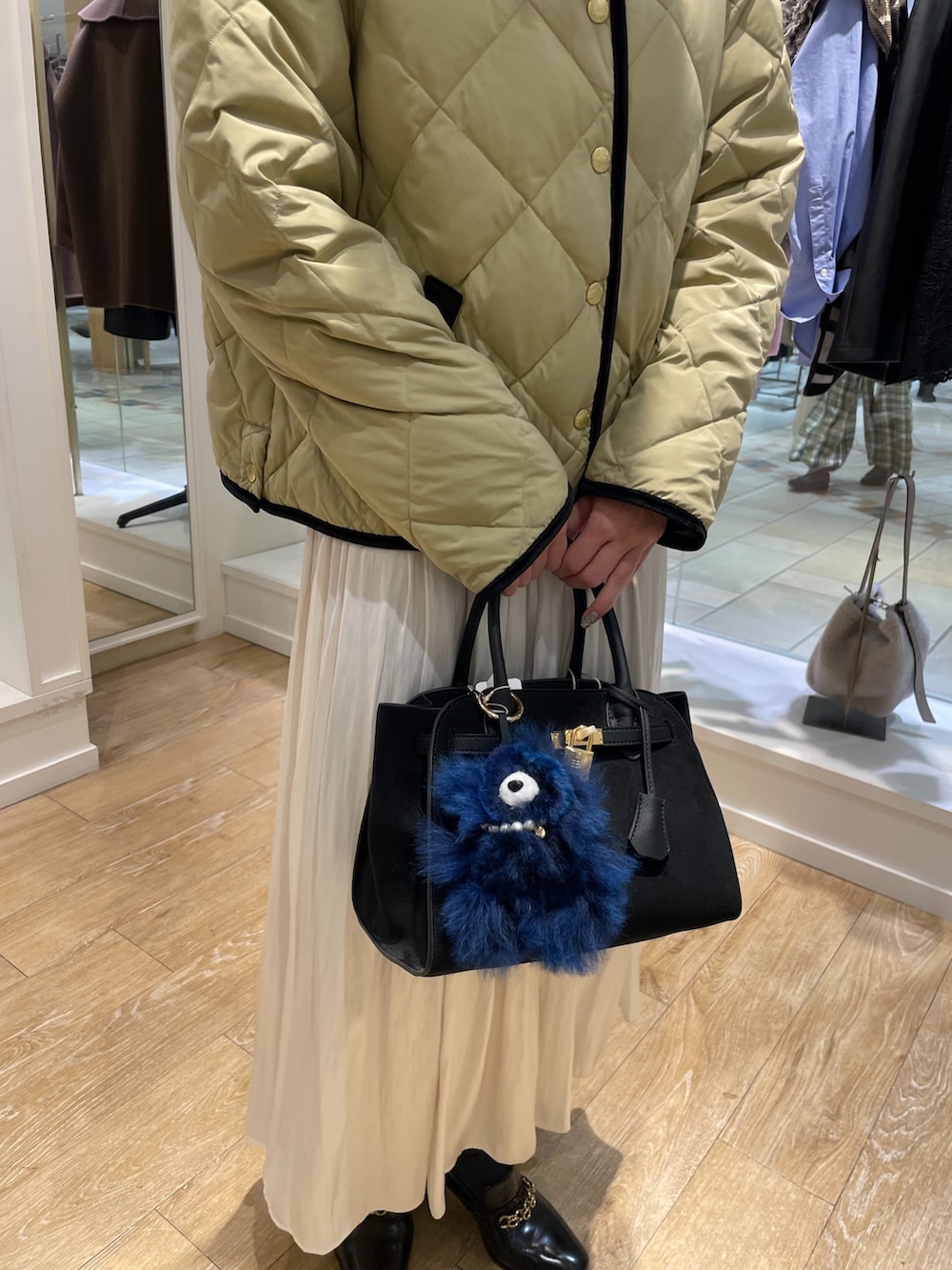 ブルー系のシャツ/ブラウス、ベージュ系のダウンジャケット/コート、ホワイト系のスカートを着用したレディースの秋コーディネートの10枚目の写真