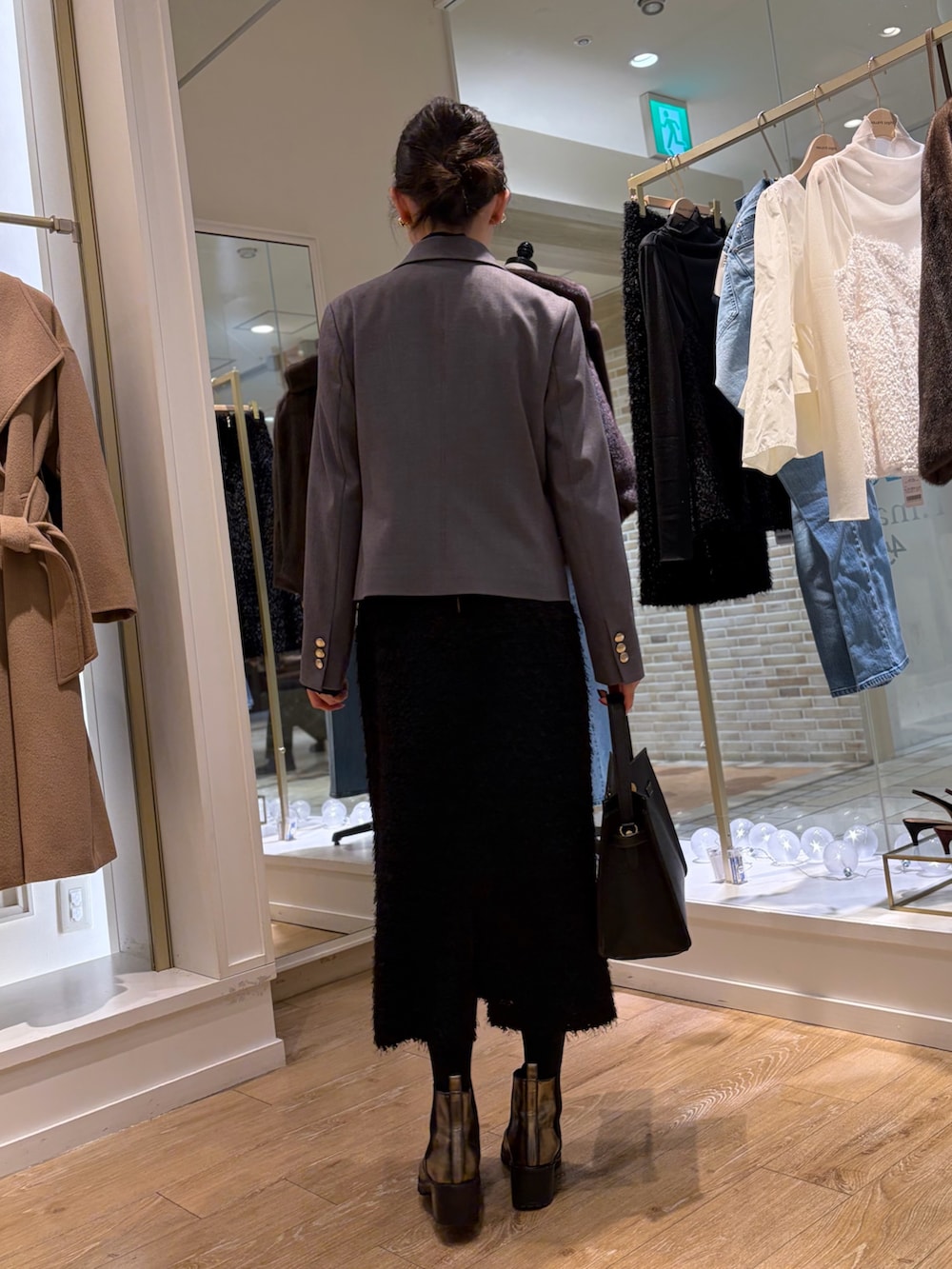 ブラック系のシャツ/ブラウス、グレー系のテーラードジャケット、ブラック系のスカートを着用したレディースの秋コーディネートの3枚目の写真