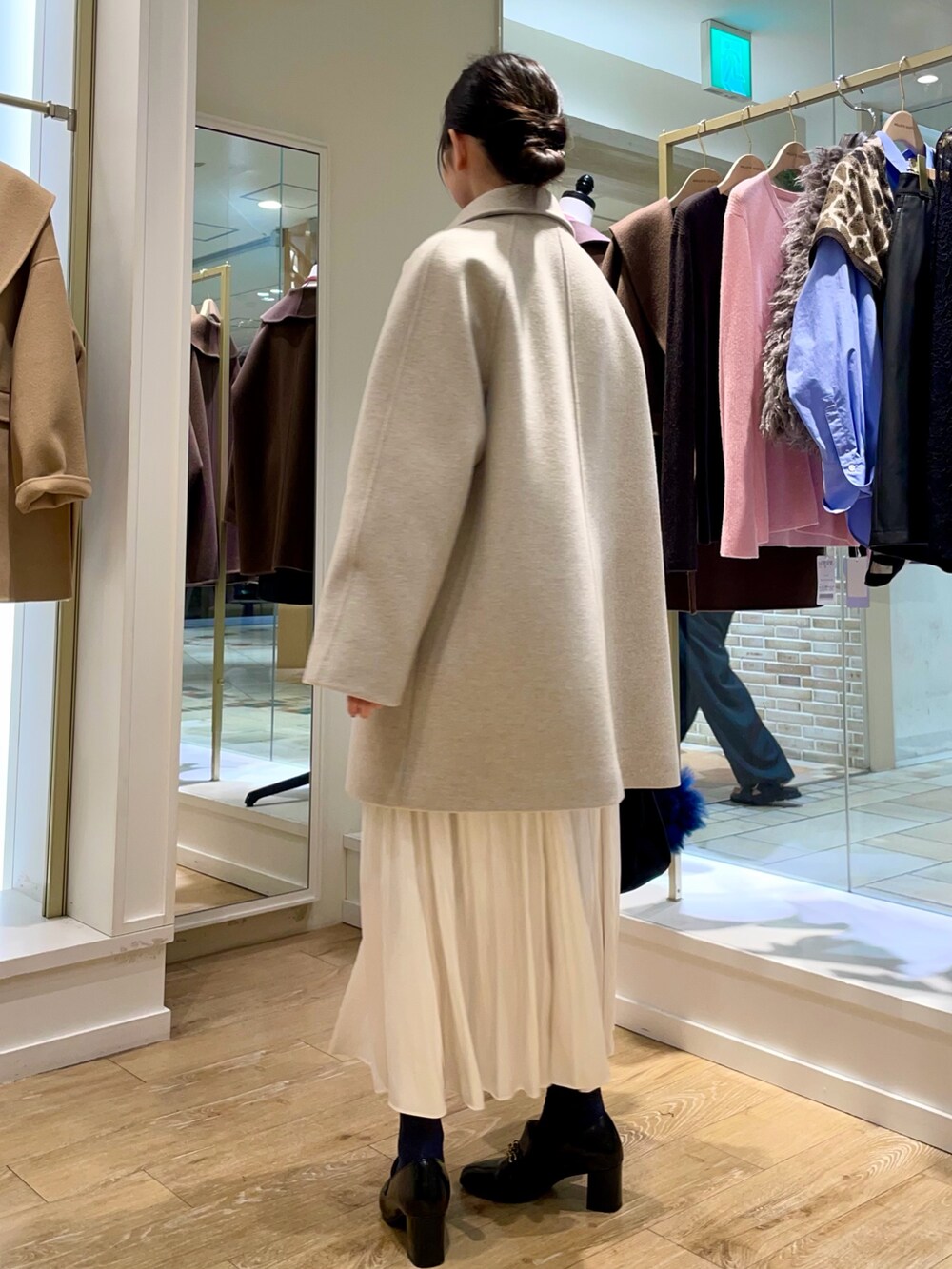 ベージュ系のステンカラーコート、ブルー系のシャツ/ブラウス、ブラック系のトートバッグを着用したレディースの秋コーディネートの3枚目の写真