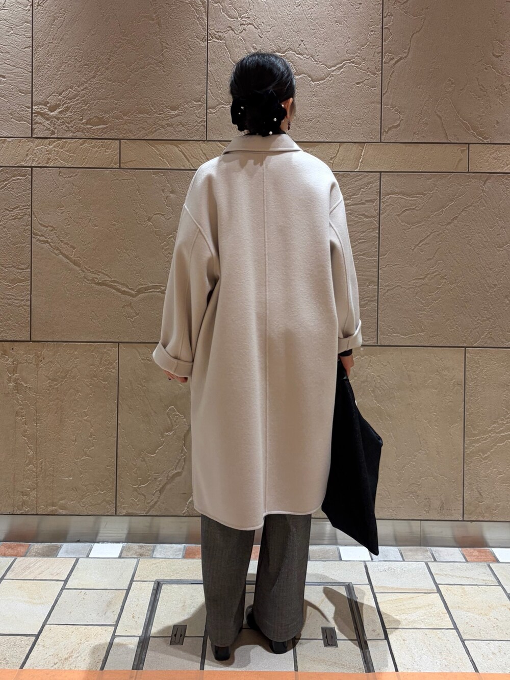 ベージュ系のステンカラーコート、グレー系のニット/セーター、ブラック系のキャミソールを着用したレディースの冬コーディネートの3枚目の写真