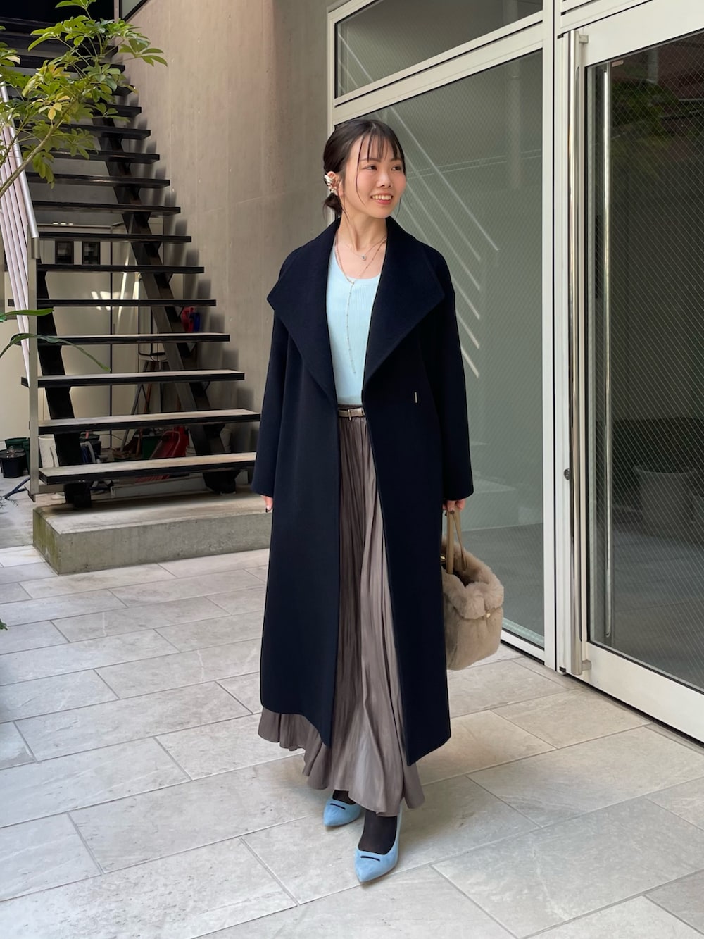 ブルー系のニット/セーター、ベージュ系のトートバッグ、グリーン系のスカートを着用したレディースの秋コーディネートの6枚目の写真