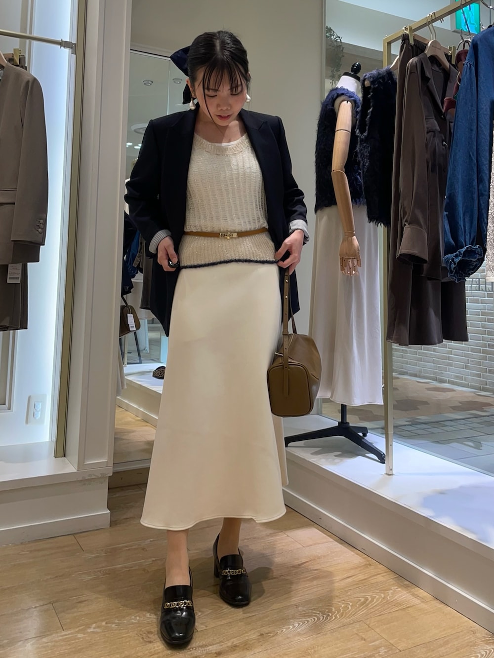 ブルー系のテーラードジャケット、ホワイト系のタンクトップ、ブラウン系のショルダーバッグを着用したレディースの秋コーディネートの5枚目の写真