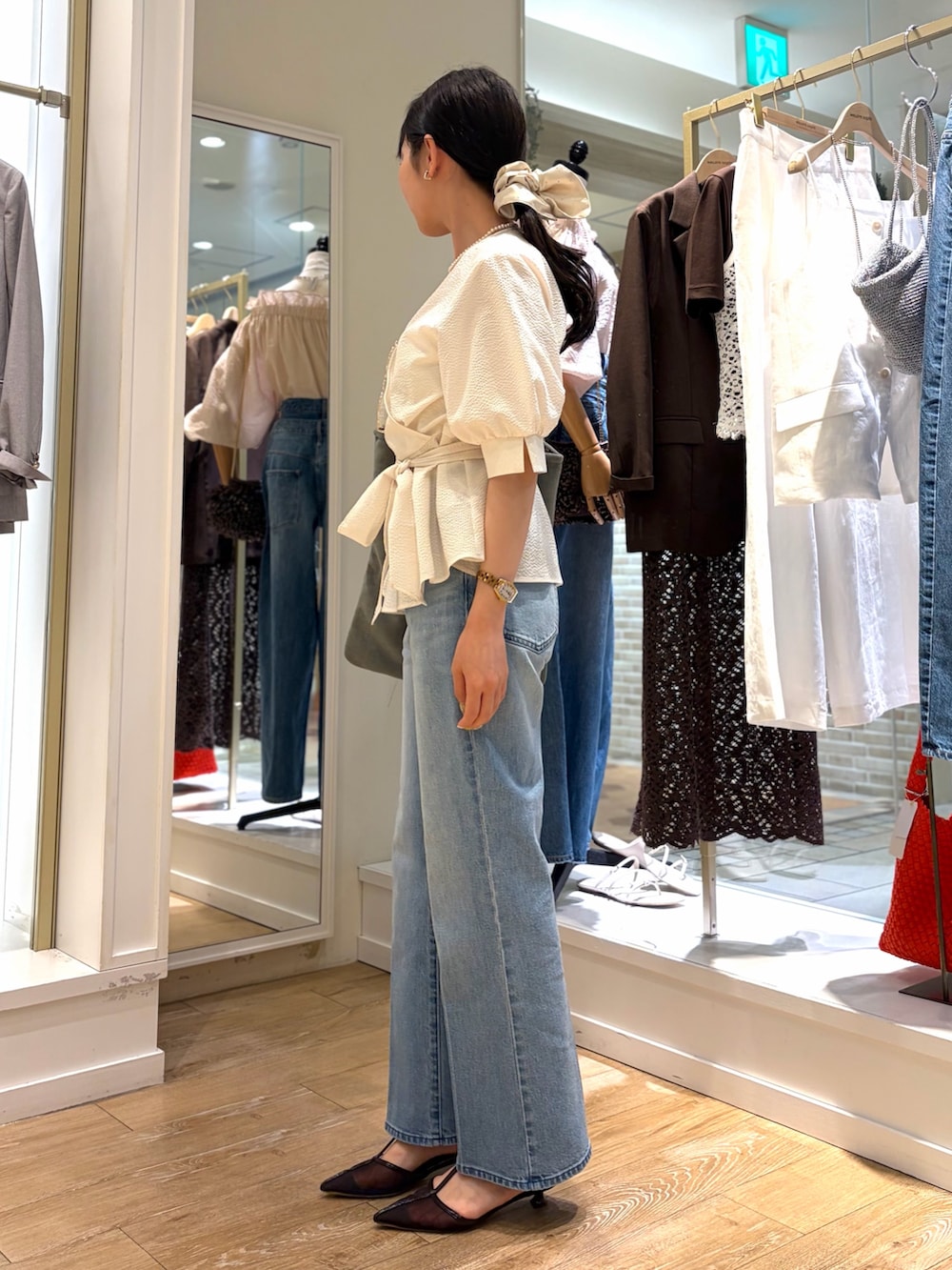 ホワイト系のシャツ/ブラウス、ブラウン系のトートバッグ、ブルー系のデニムパンツを着用したレディースの春コーディネートの3枚目の写真