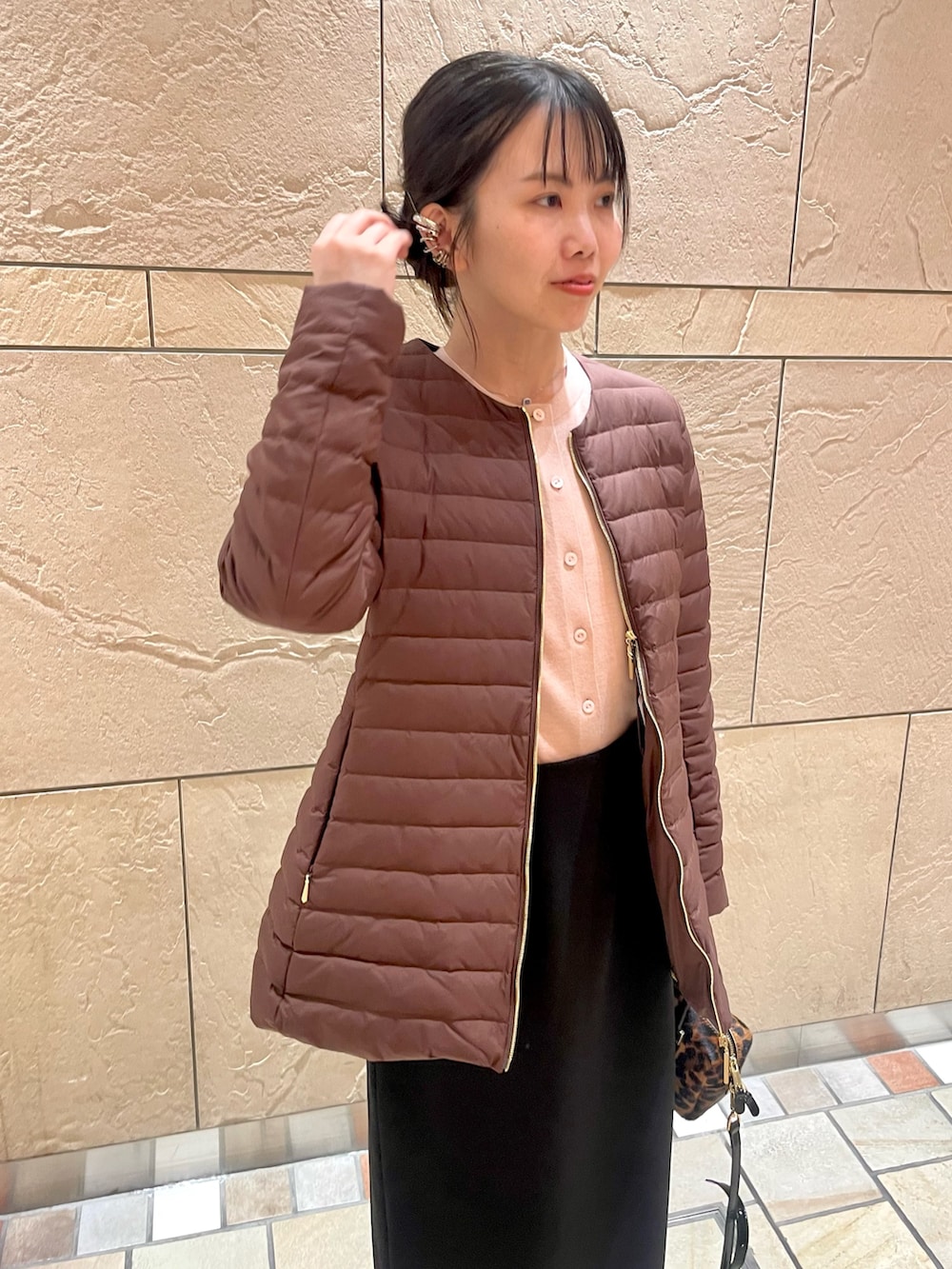 ブラウン系のダウンジャケット/コート、イエロー系のカーディガン/ボレロ、ブラック系のスカートを着用したレディースの秋コーディネートの4枚目の写真