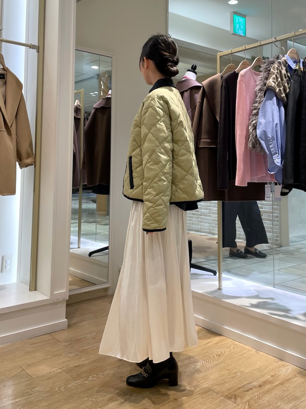 ブルー系のシャツ/ブラウス、ベージュ系のダウンジャケット/コート、ホワイト系のスカートを着用したレディースの秋コーディネートの3枚目の写真