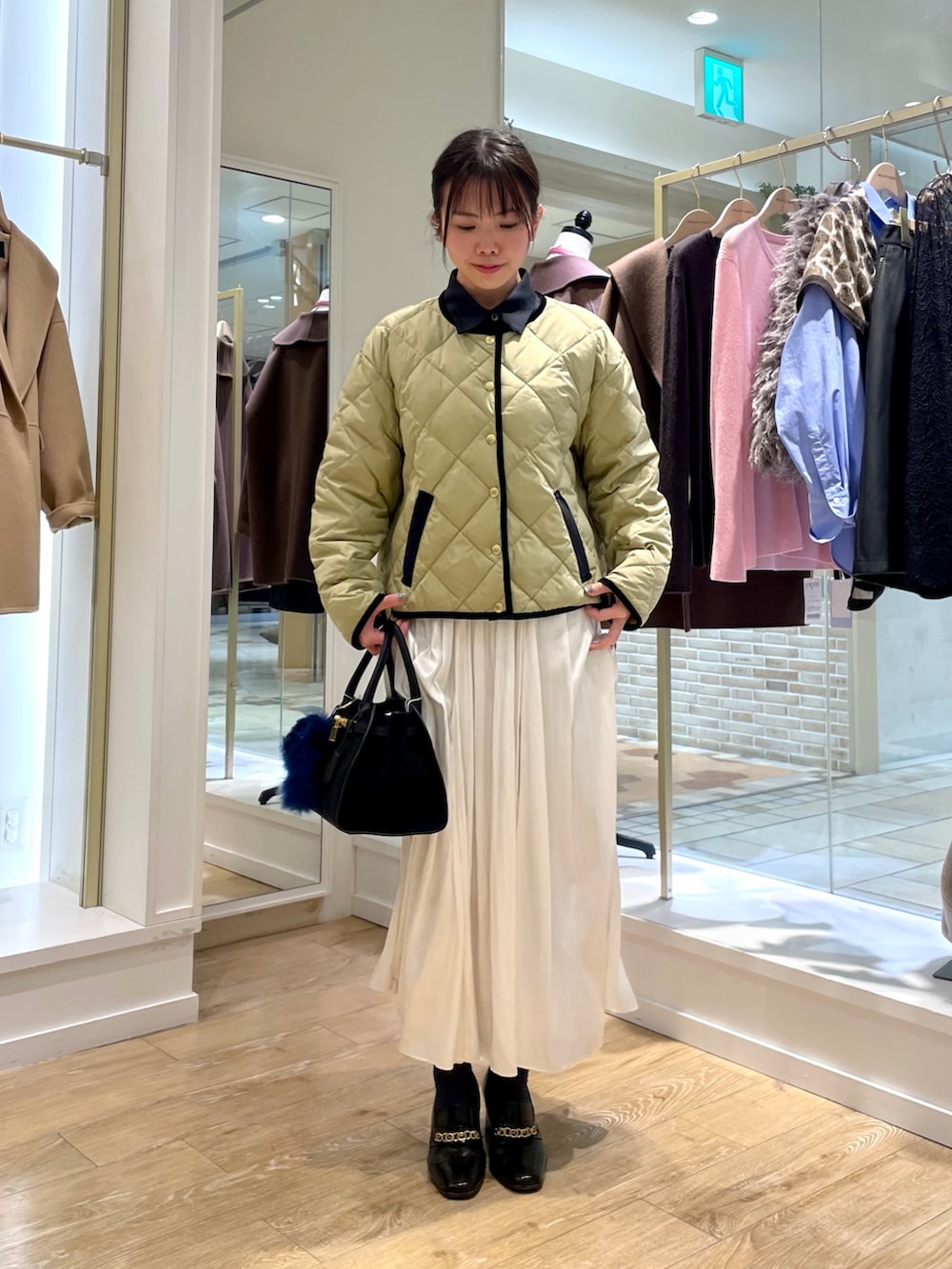 ブルー系のシャツ/ブラウス、ベージュ系のダウンジャケット/コート、ホワイト系のスカートを着用したレディースの秋コーディネートの8枚目の写真