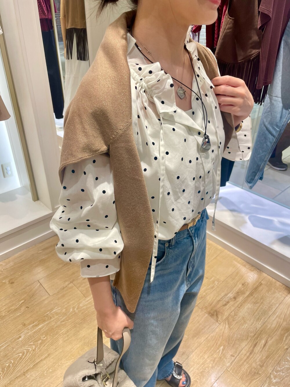 ベージュ系のショルダーバッグ、ブルー系のデニムパンツ、ホワイト系のシャツ/ブラウスを着用したレディースの秋コーディネートの5枚目の写真