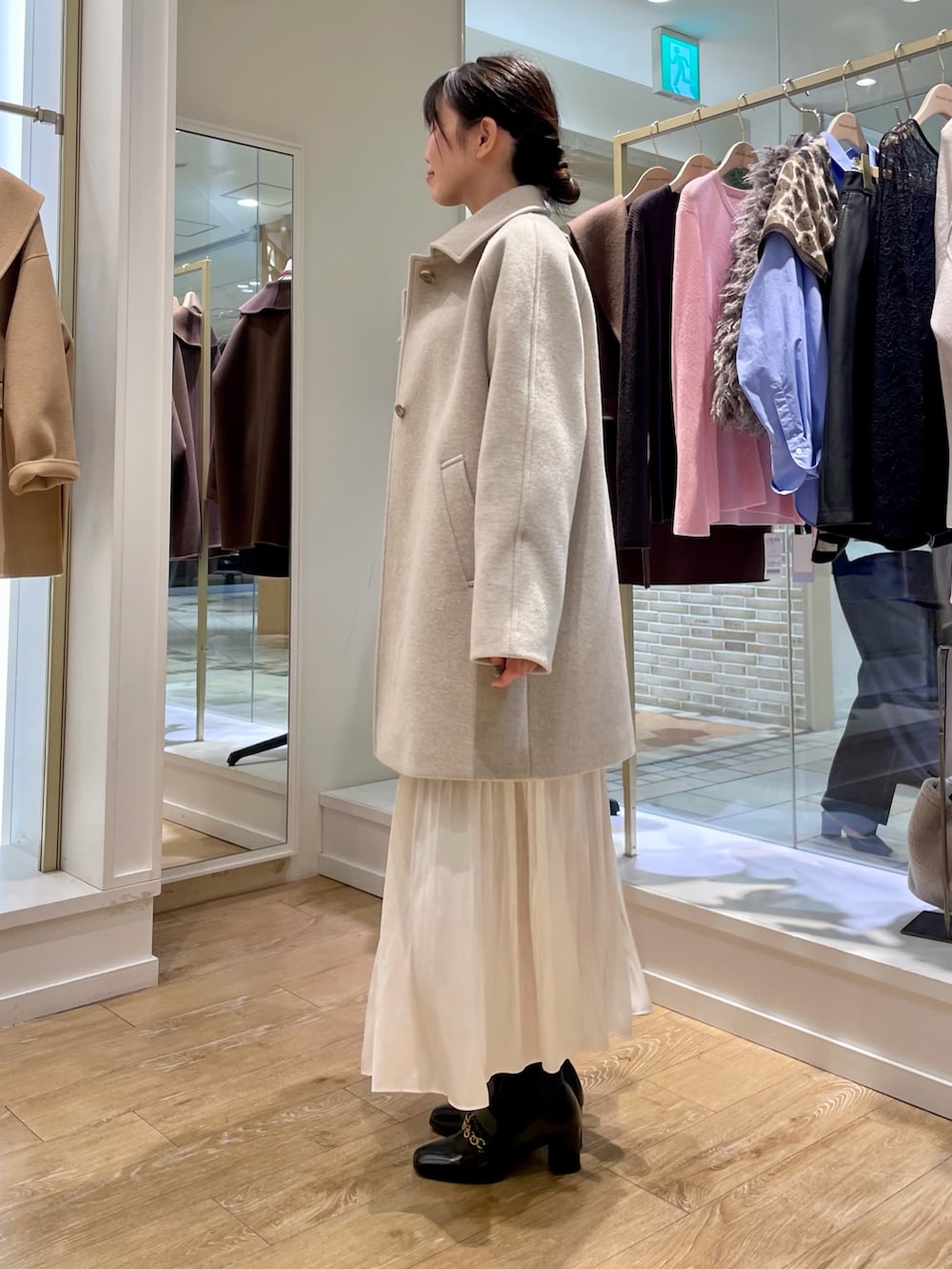 ベージュ系のステンカラーコート、ブルー系のシャツ/ブラウス、ブラック系のトートバッグを着用したレディースの秋コーディネートの2枚目の写真