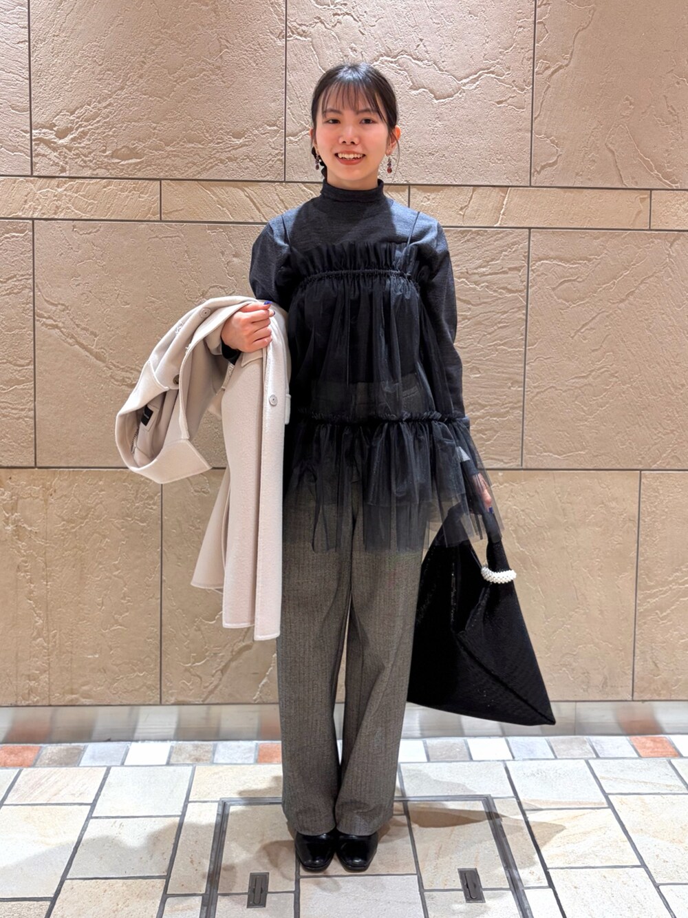 ベージュ系のステンカラーコート、グレー系のニット/セーター、ブラック系のキャミソールを着用したレディースの冬コーディネートの6枚目の写真