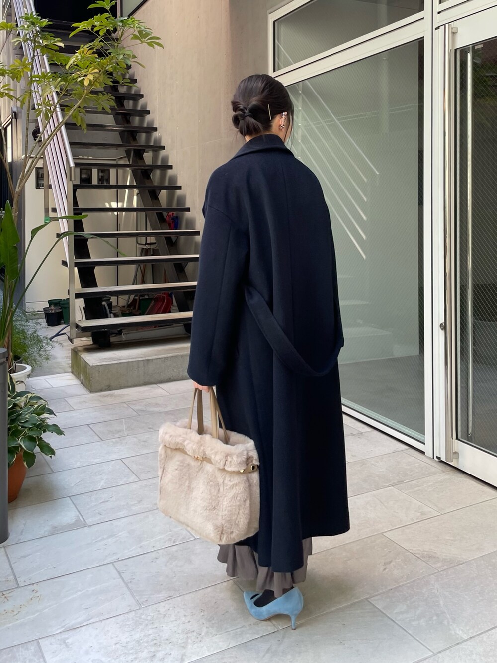 ブルー系のニット/セーター、ベージュ系のトートバッグ、グリーン系のスカートを着用したレディースの秋コーディネートの3枚目の写真