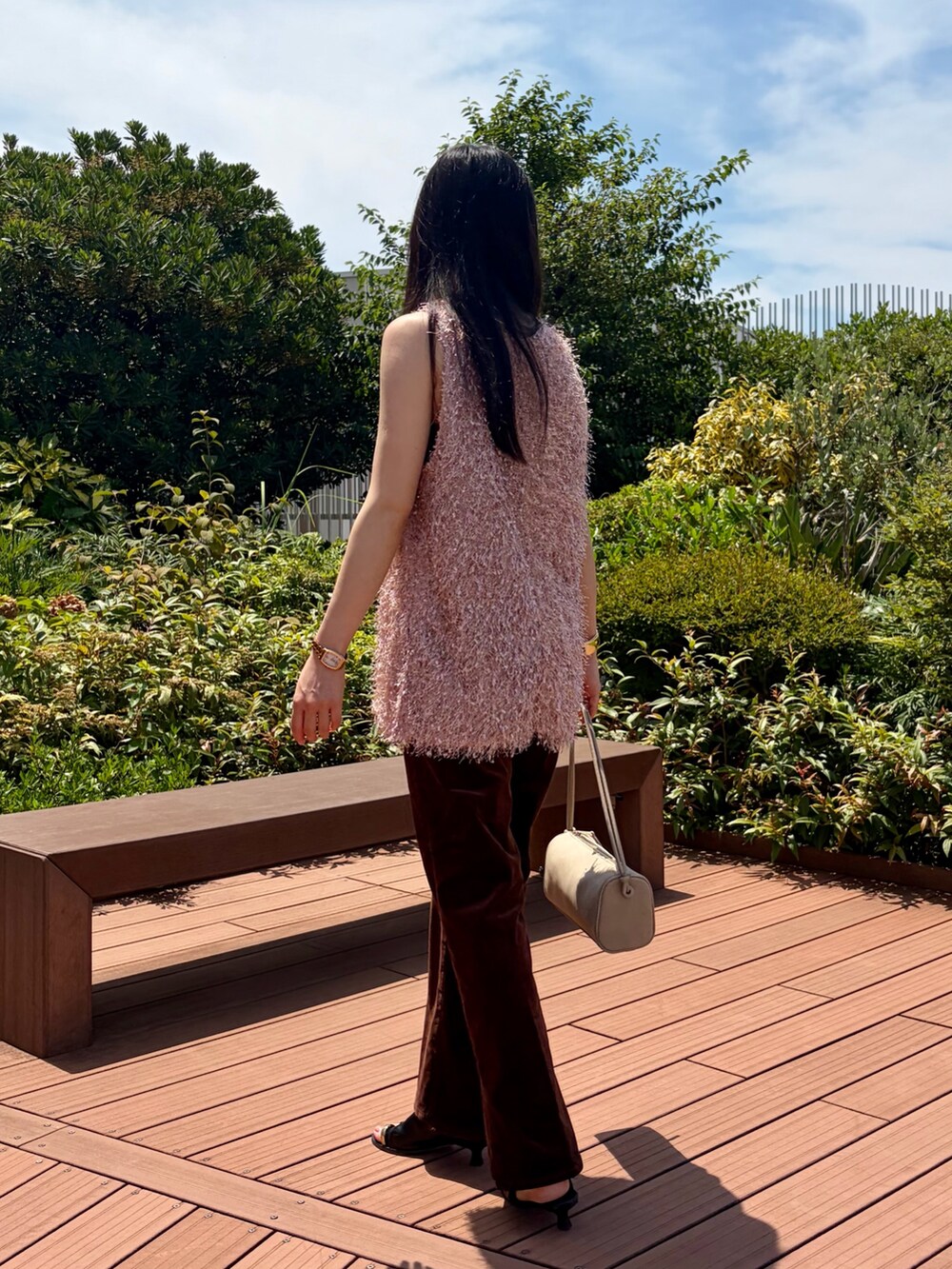 ピンク系のベスト、ブラウン系のその他パンツ、ベージュ系のショルダーバッグを着用したレディースの夏コーディネートの3枚目の写真