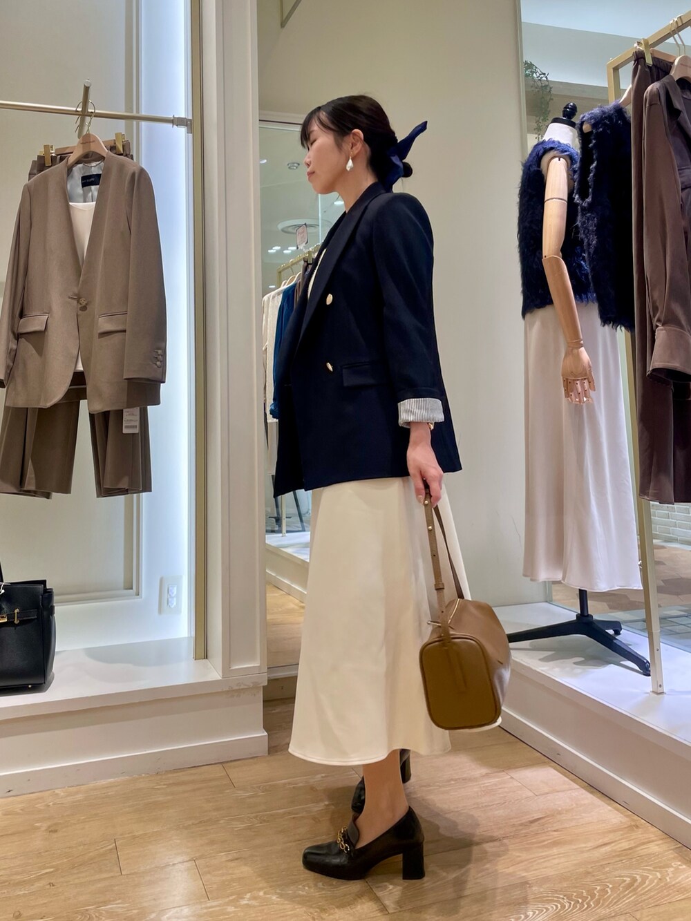 ブルー系のテーラードジャケット、ホワイト系のタンクトップ、ブラウン系のショルダーバッグを着用したレディースの秋コーディネートの2枚目の写真