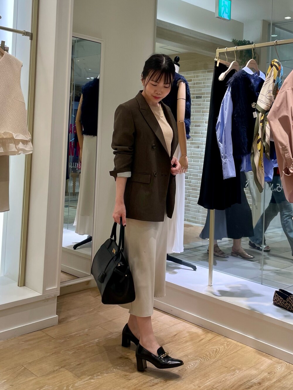 ブラウン系のテーラードジャケット、イエロー系のニット/セーター、ブラック系のショルダーバッグを着用したレディースの秋コーディネートの5枚目の写真