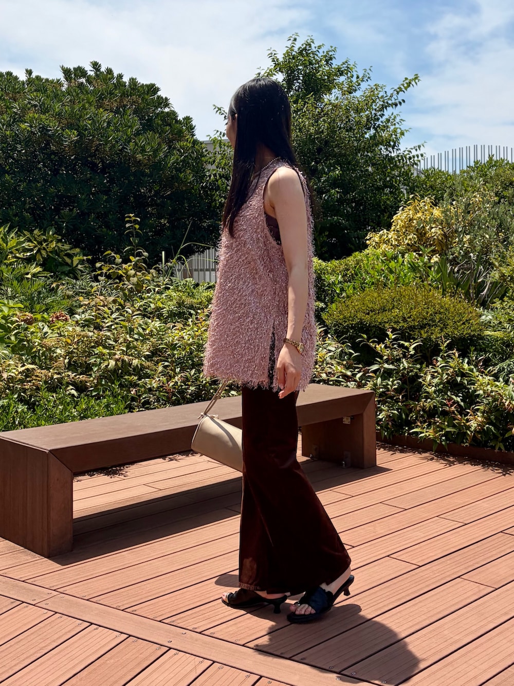 ピンク系のベスト、ブラウン系のその他パンツ、ベージュ系のショルダーバッグを着用したレディースの夏コーディネートの2枚目の写真