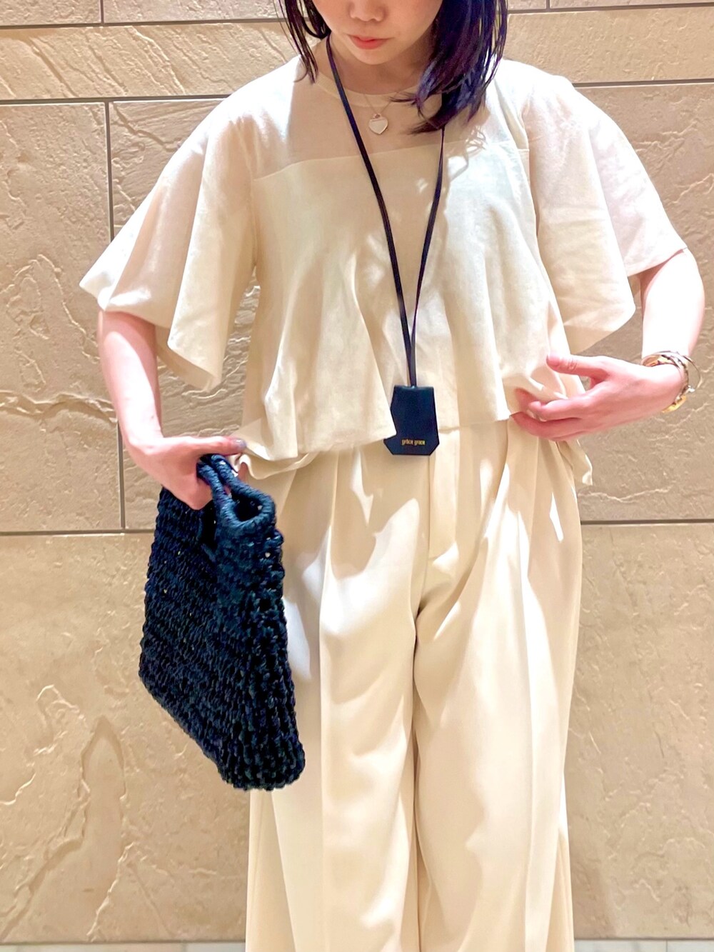 ベージュ系のニット/セーター、ホワイト系のその他パンツ、ブラック系のかごバッグを着用したレディースの夏コーディネートの4枚目の写真