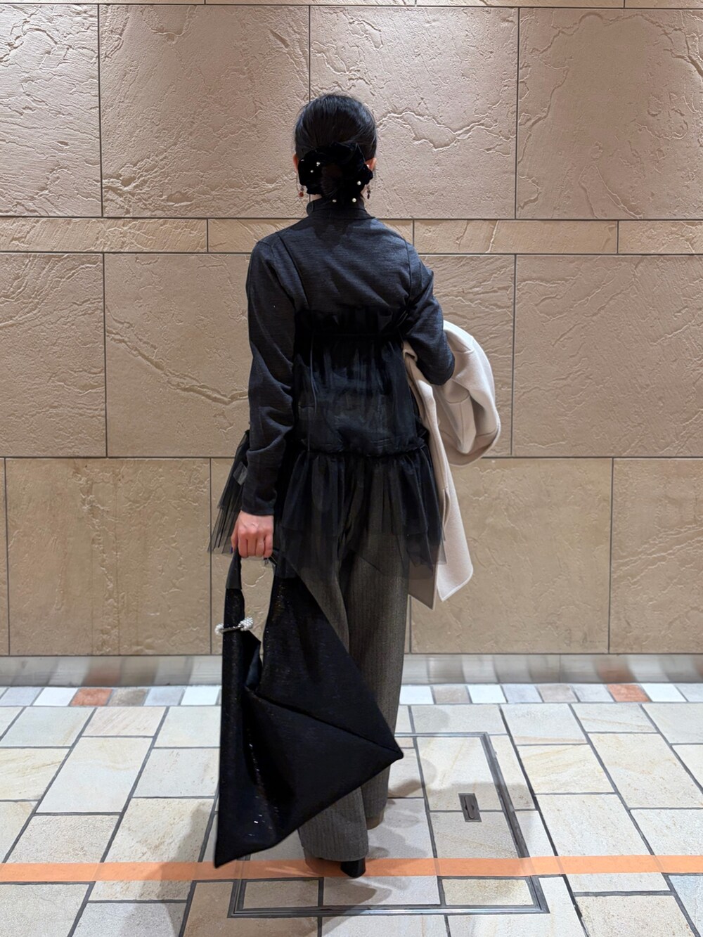 ベージュ系のステンカラーコート、グレー系のニット/セーター、ブラック系のキャミソールを着用したレディースの冬コーディネートの8枚目の写真