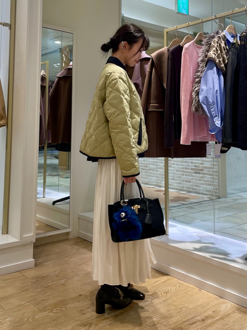 ブルー系のシャツ/ブラウス、ベージュ系のダウンジャケット/コート、ホワイト系のスカートを着用したレディースの秋コーディネートの6枚目の写真