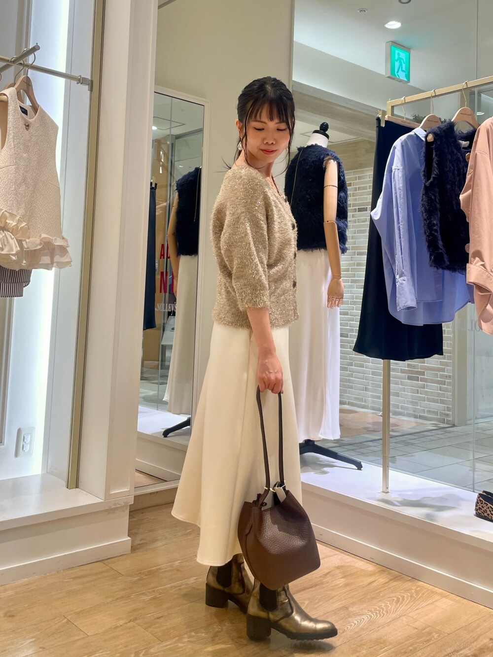 イエロー系のカーディガン/ボレロ、ホワイト系のスカート、ブラウン系のショルダーバッグを着用したレディースの秋コーディネートの7枚目の写真