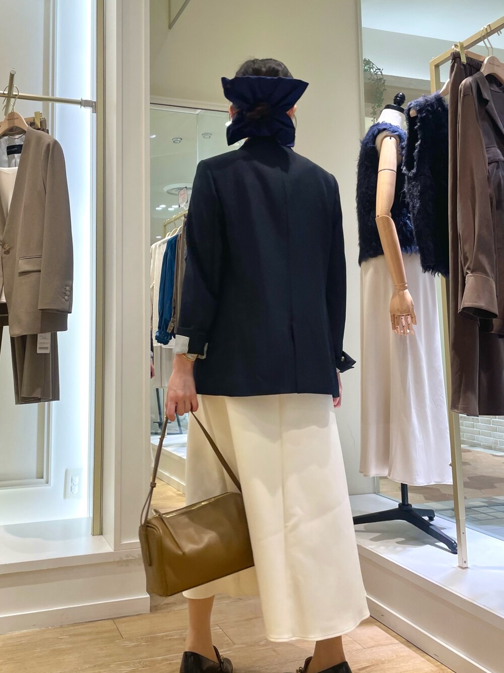 ブルー系のテーラードジャケット、ホワイト系のタンクトップ、ブラウン系のショルダーバッグを着用したレディースの秋コーディネートの3枚目の写真