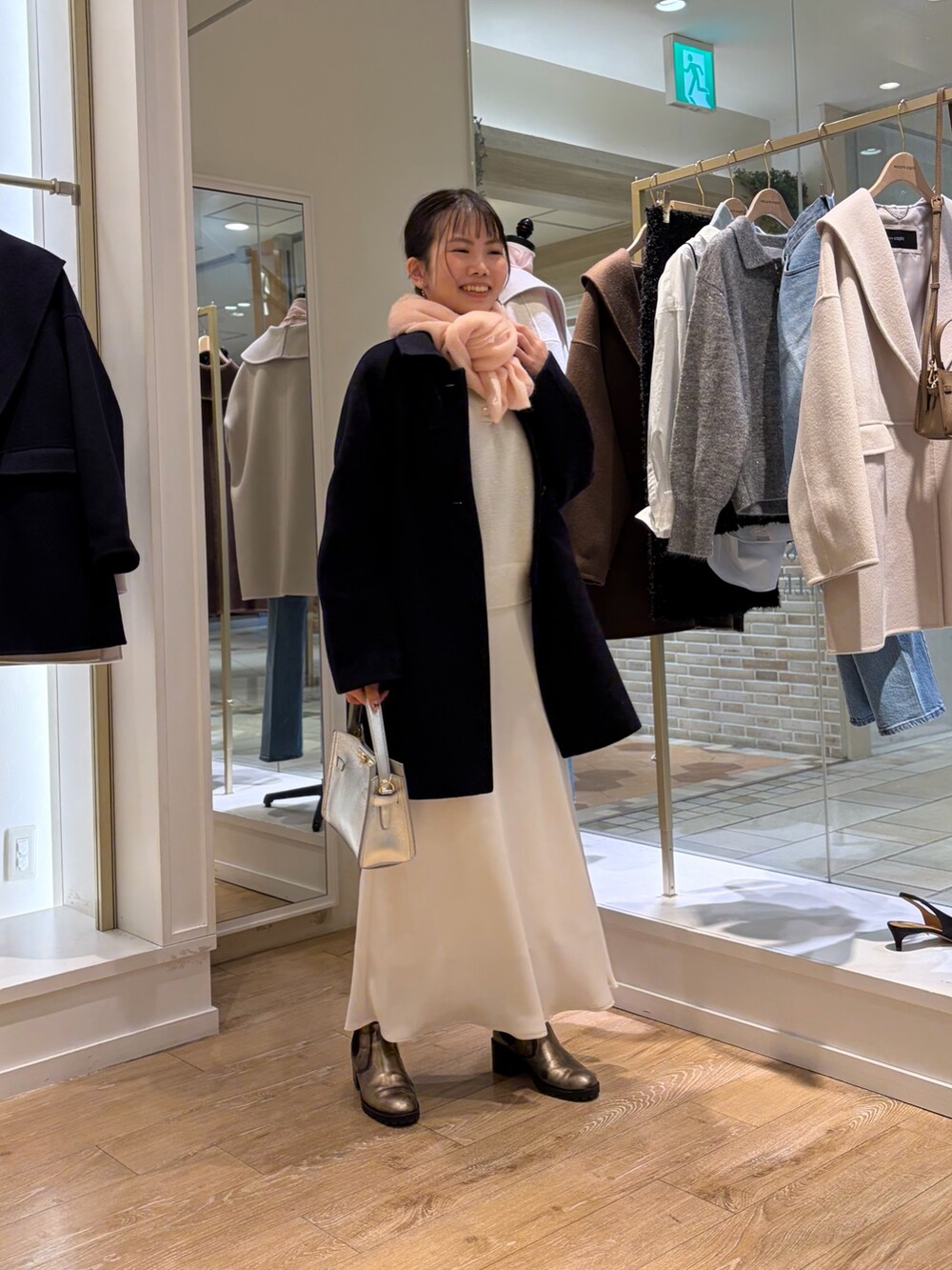 ホワイト系のニット/セーター、ホワイト系のスカート、ブルー系のステンカラーコートを着用したレディースの秋コーディネートの4枚目の写真