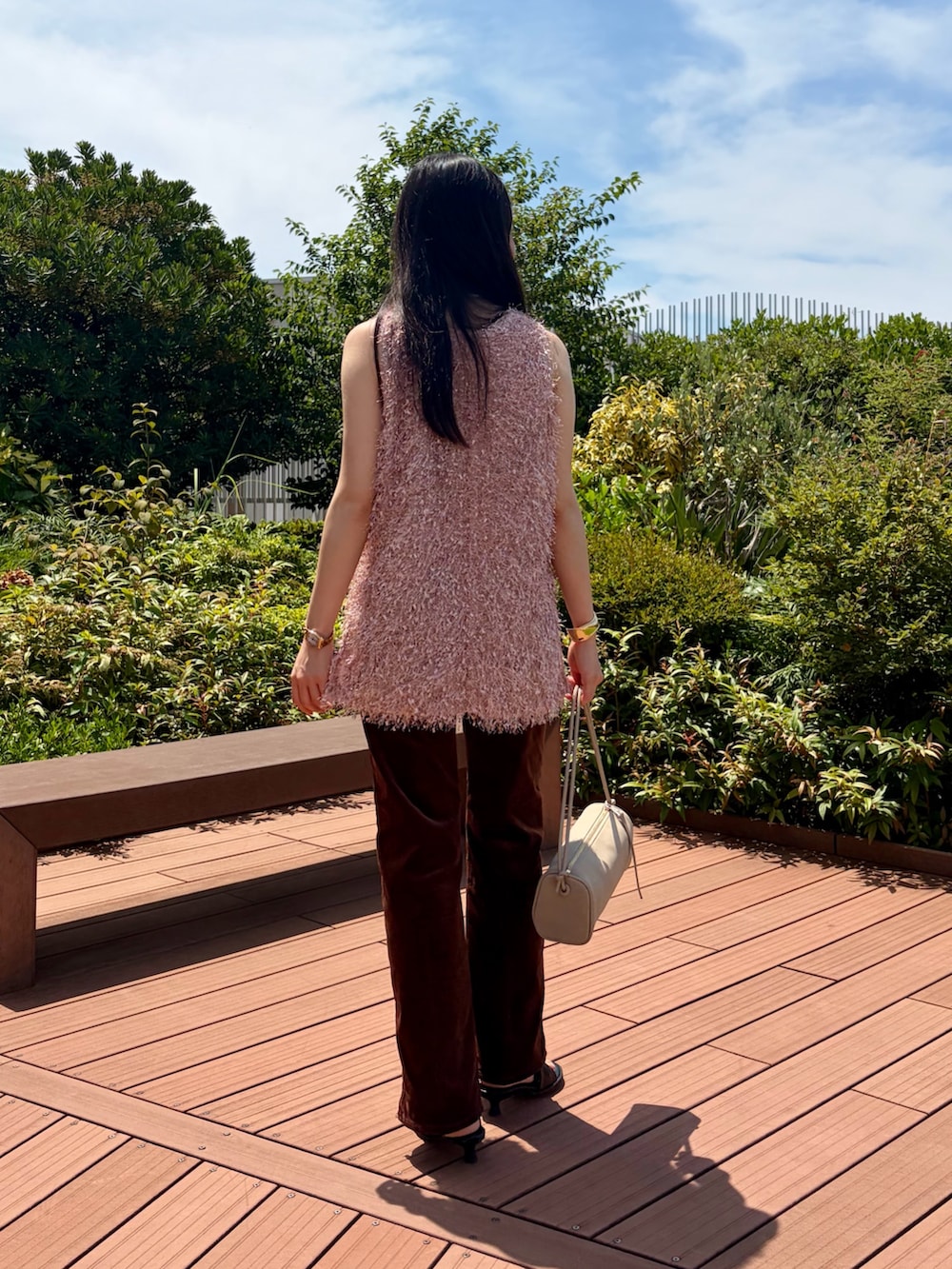 ピンク系のベスト、ブラウン系のその他パンツ、ベージュ系のショルダーバッグを着用したレディースの夏コーディネートの4枚目の写真