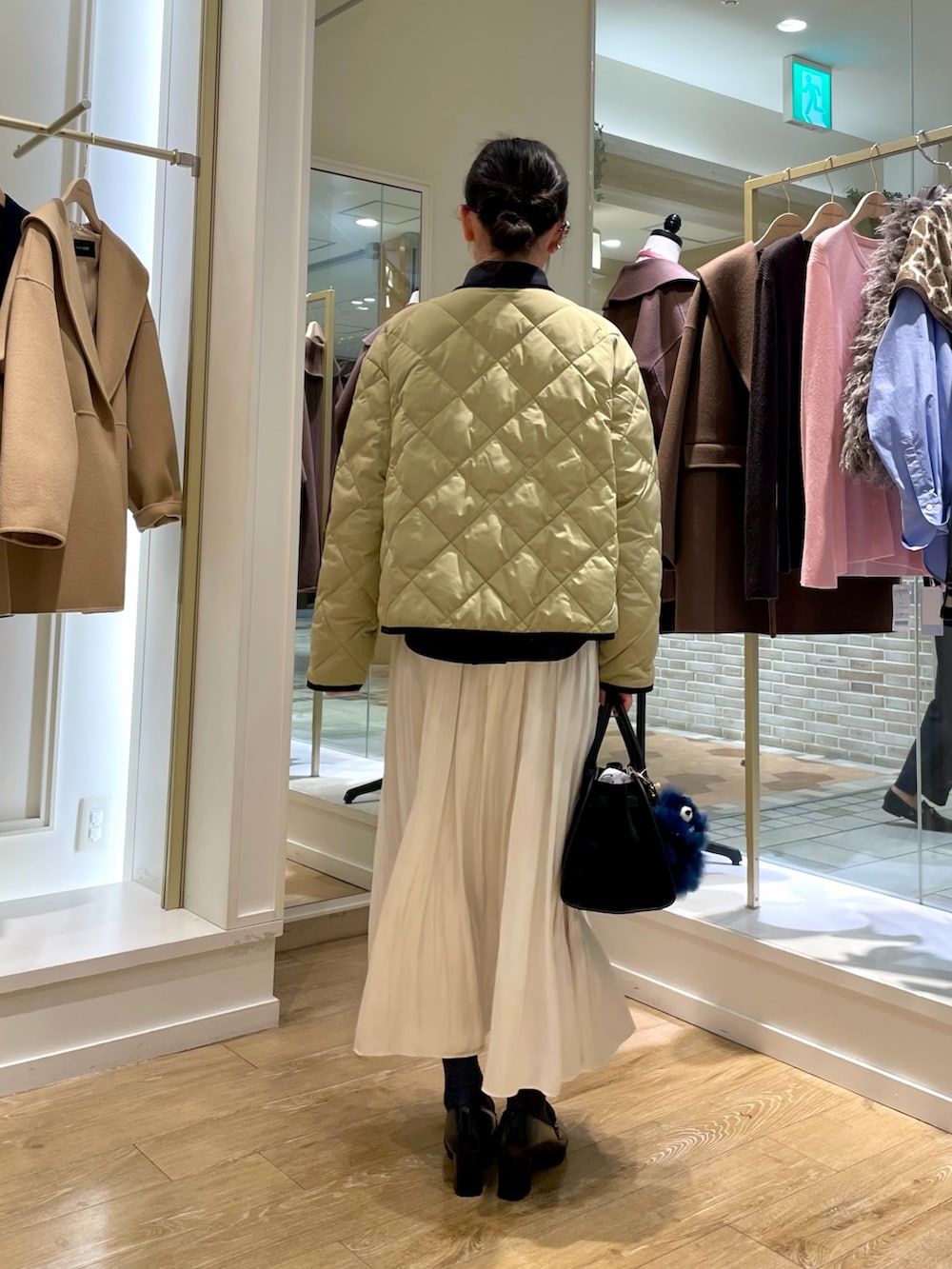 ブルー系のシャツ/ブラウス、ベージュ系のダウンジャケット/コート、ホワイト系のスカートを着用したレディースの秋コーディネートの4枚目の写真