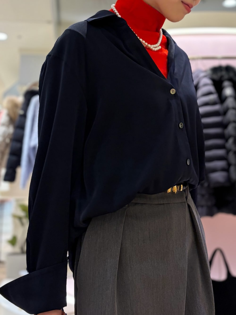 レッド系のニット/セーター、ホワイト系のシャツ/ブラウス、ベージュ系のショルダーバッグを着用したレディースの冬コーディネートの5枚目の写真