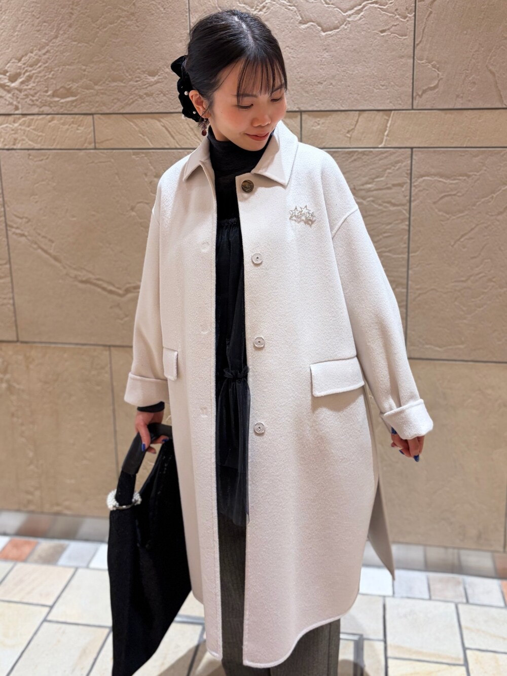 ベージュ系のステンカラーコート、グレー系のニット/セーター、ブラック系のキャミソールを着用したレディースの冬コーディネートの5枚目の写真