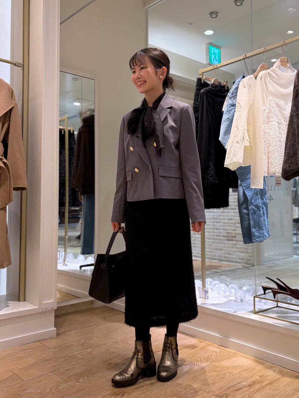 ブラック系のシャツ/ブラウス、グレー系のテーラードジャケット、ブラック系のスカートを着用したレディースの秋コーディネートの2枚目の写真