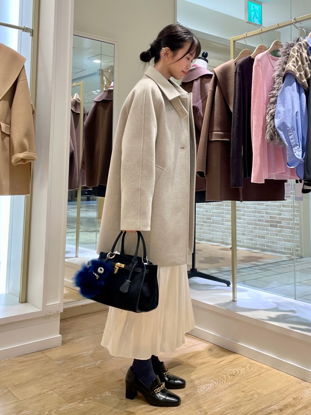 ベージュ系のステンカラーコート、ブルー系のシャツ/ブラウス、ブラック系のトートバッグを着用したレディースの秋コーディネートの6枚目の写真