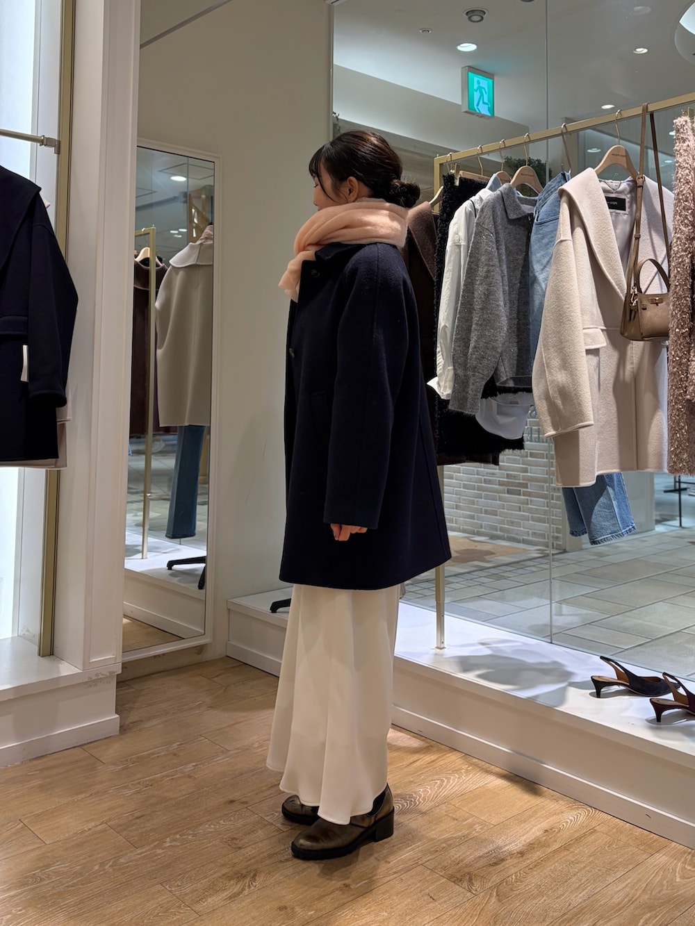 ホワイト系のニット/セーター、ホワイト系のスカート、ブルー系のステンカラーコートを着用したレディースの秋コーディネートの2枚目の写真