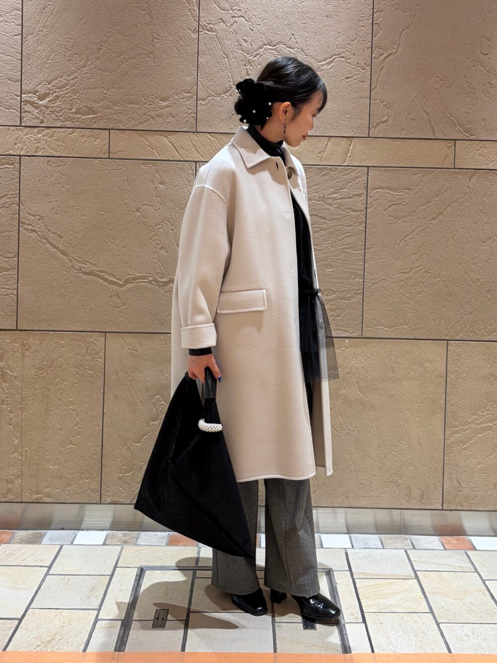 ベージュ系のステンカラーコート、グレー系のニット/セーター、ブラック系のキャミソールを着用したレディースの冬コーディネートの4枚目の写真