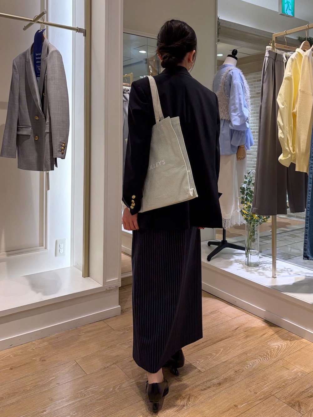 グレー系のトートバッグ、ブルー系のテーラードジャケット、ブルー系のキャミソールを着用したレディースの冬コーディネートの3枚目の写真