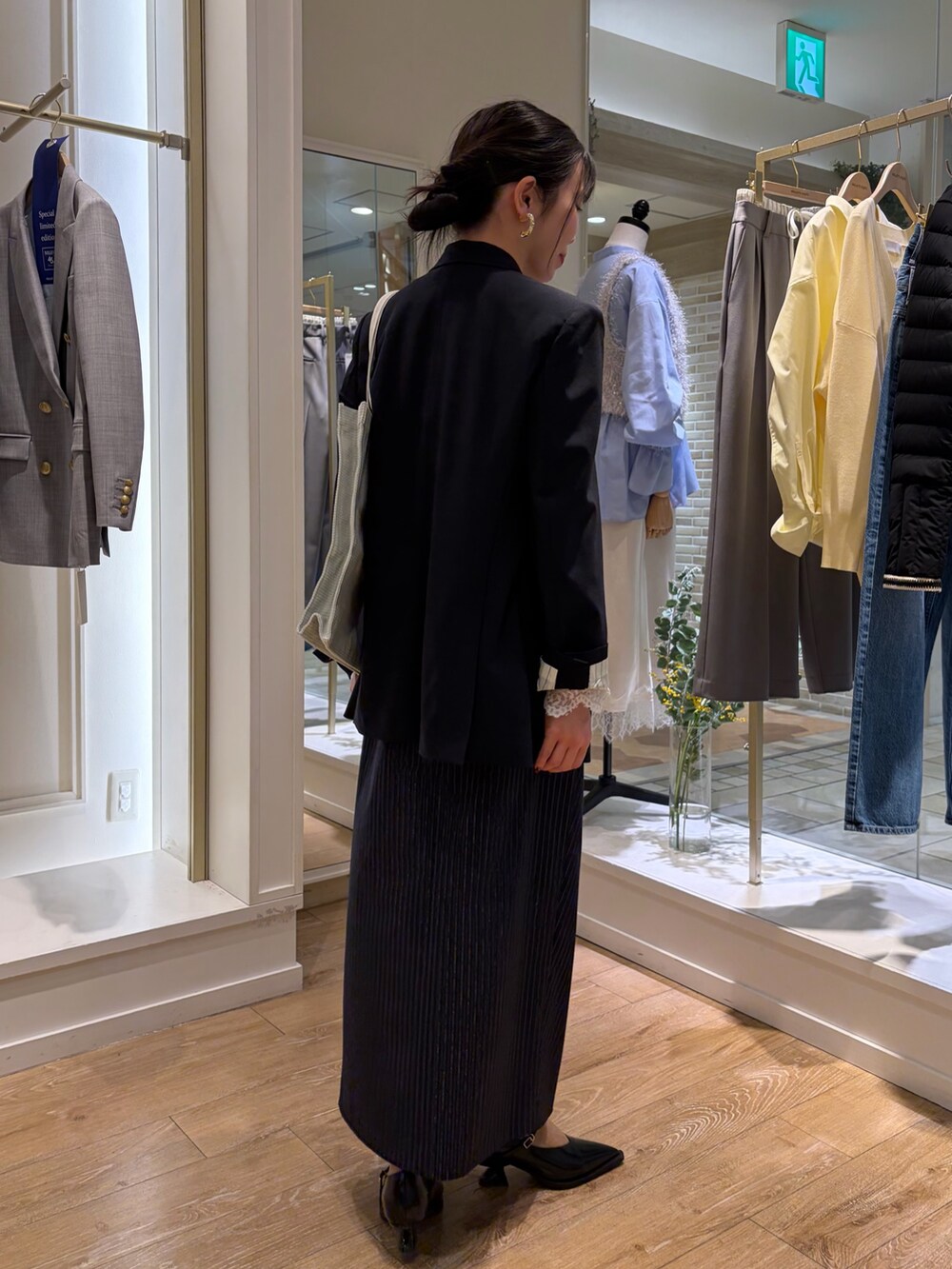 グレー系のトートバッグ、ブルー系のテーラードジャケット、ブルー系のキャミソールを着用したレディースの冬コーディネートの4枚目の写真