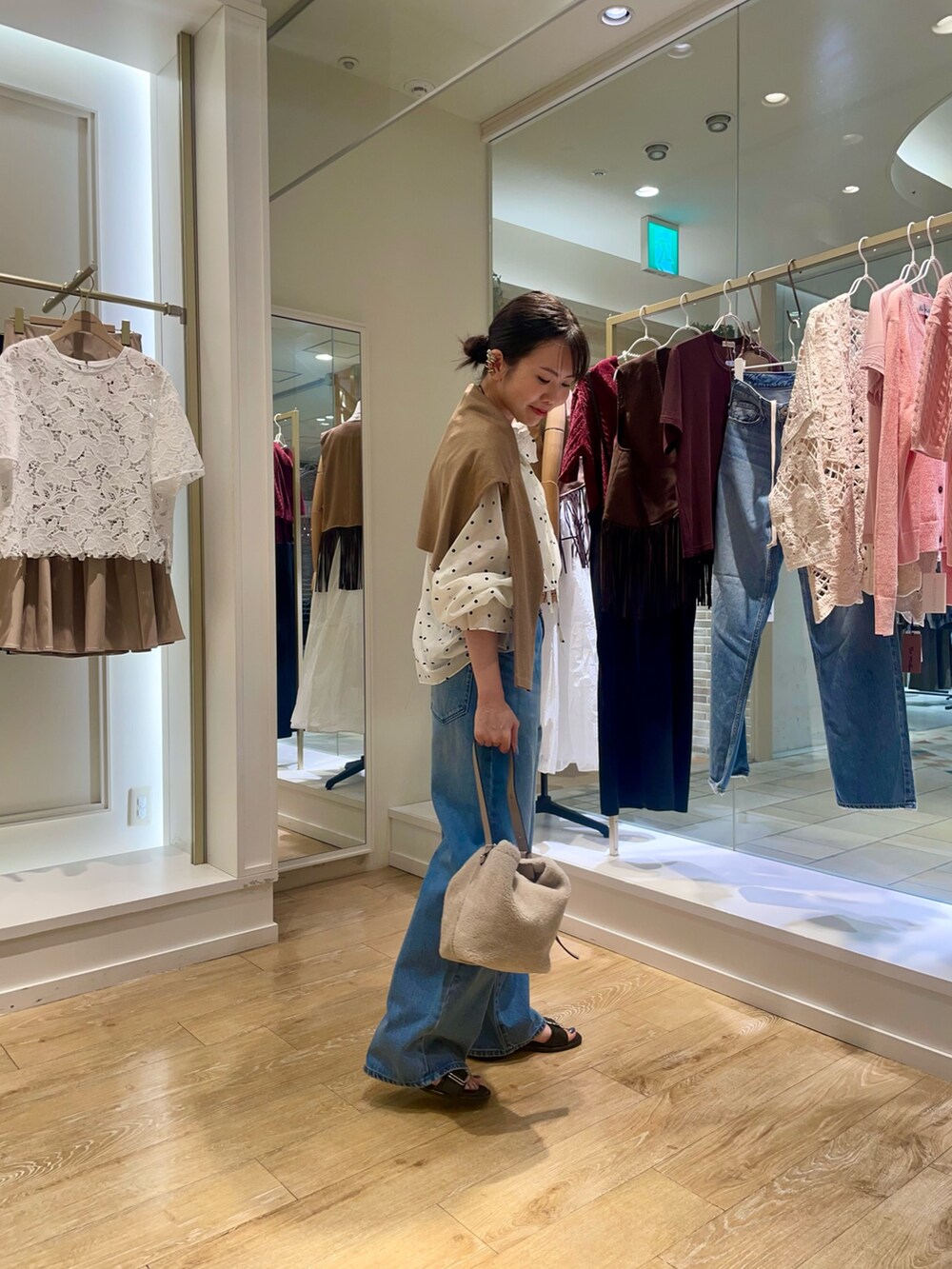 ベージュ系のショルダーバッグ、ブルー系のデニムパンツ、ホワイト系のシャツ/ブラウスを着用したレディースの秋コーディネートの4枚目の写真