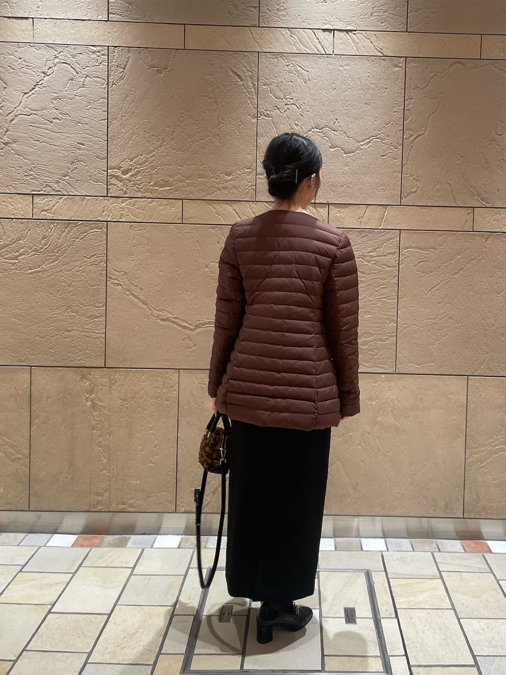 ブラウン系のダウンジャケット/コート、イエロー系のカーディガン/ボレロ、ブラック系のスカートを着用したレディースの秋コーディネートの3枚目の写真