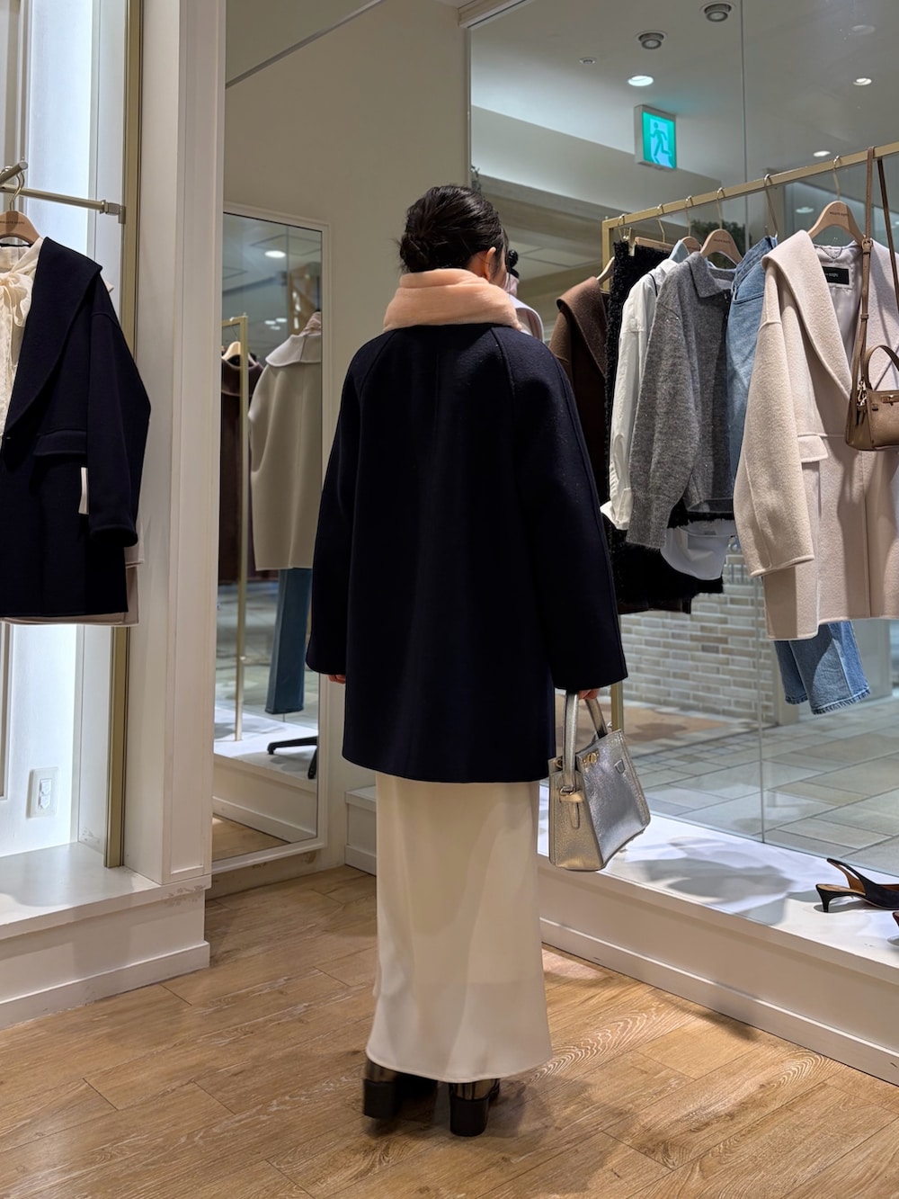 ホワイト系のニット/セーター、ホワイト系のスカート、ブルー系のステンカラーコートを着用したレディースの秋コーディネートの3枚目の写真