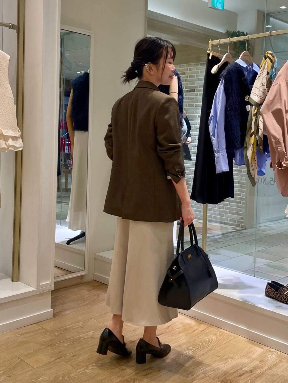 ブラウン系のテーラードジャケット、イエロー系のニット/セーター、ブラック系のショルダーバッグを着用したレディースの秋コーディネートの4枚目の写真