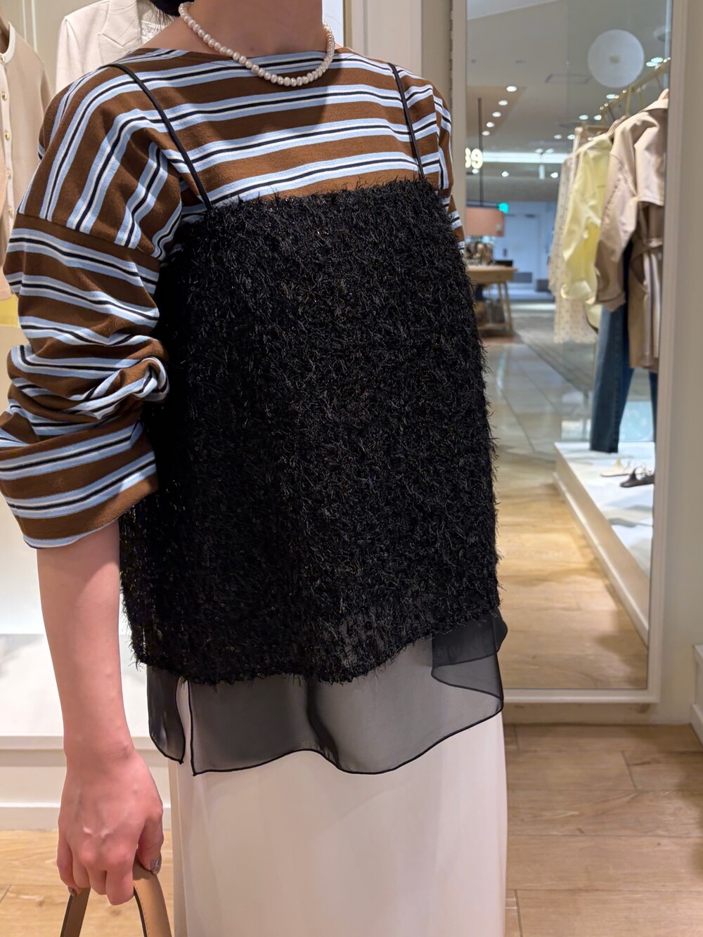 ベージュ系のTシャツ/カットソー、ブラック系のシャツ/ブラウス、ベージュ系のショルダーバッグを着用したレディースの春コーディネートの5枚目の写真