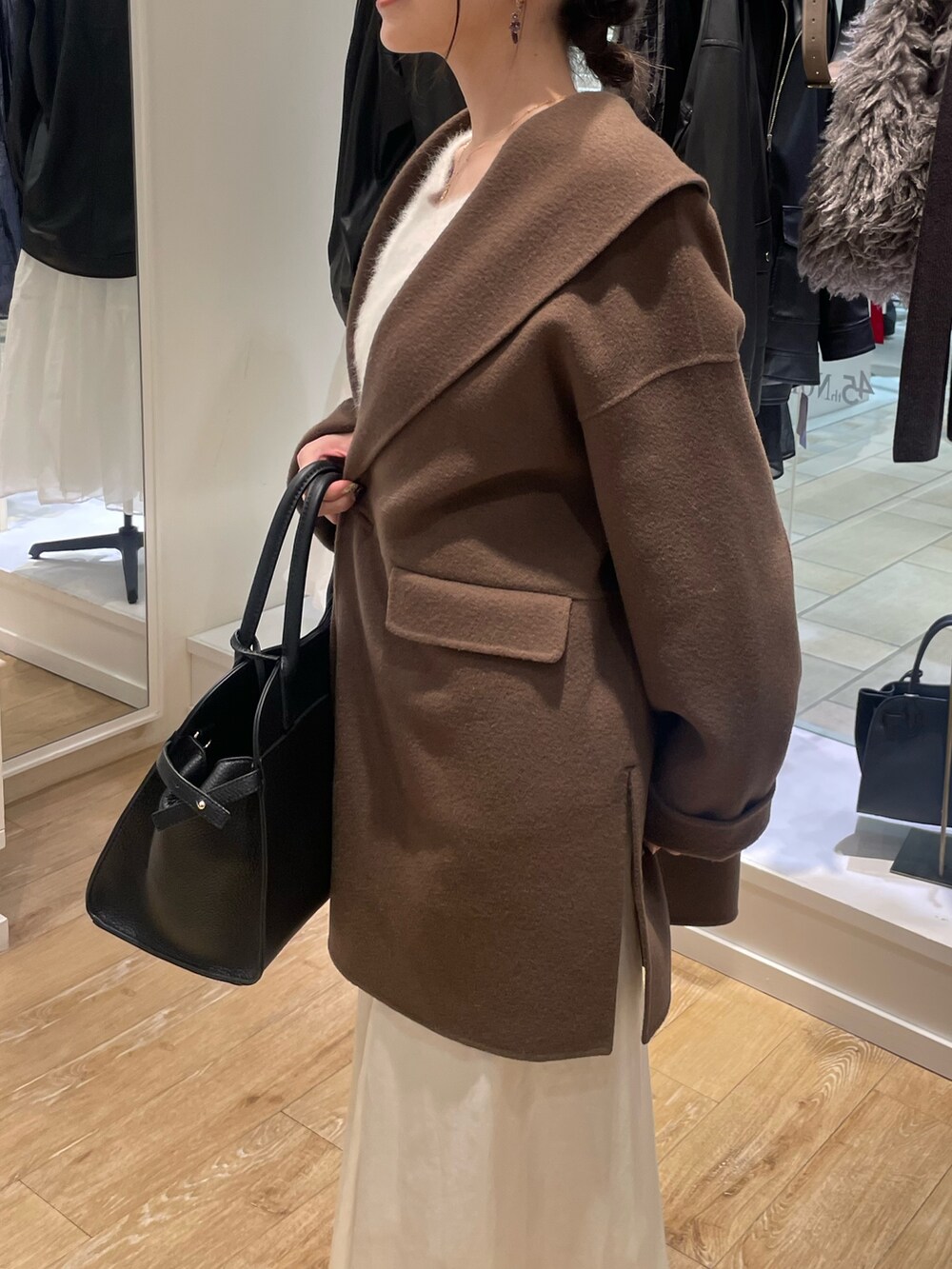 ブラウン系のその他アウター、ベージュ系のニット/セーター、ホワイト系のスカートを着用したレディースの秋コーディネートの6枚目の写真