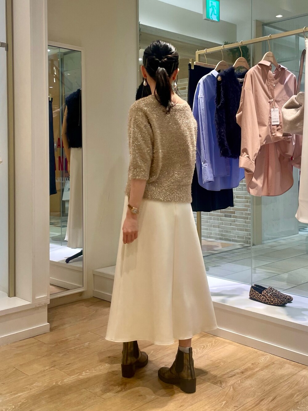 イエロー系のカーディガン/ボレロ、ホワイト系のスカート、ブラウン系のショルダーバッグを着用したレディースの秋コーディネートの3枚目の写真