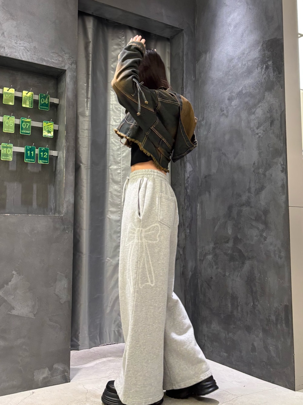 ブルー系のデニムジャケット、ブラック系のニット/セーター、グレー系のスウェットパンツを着用したレディースの冬コーディネートの2枚目の写真