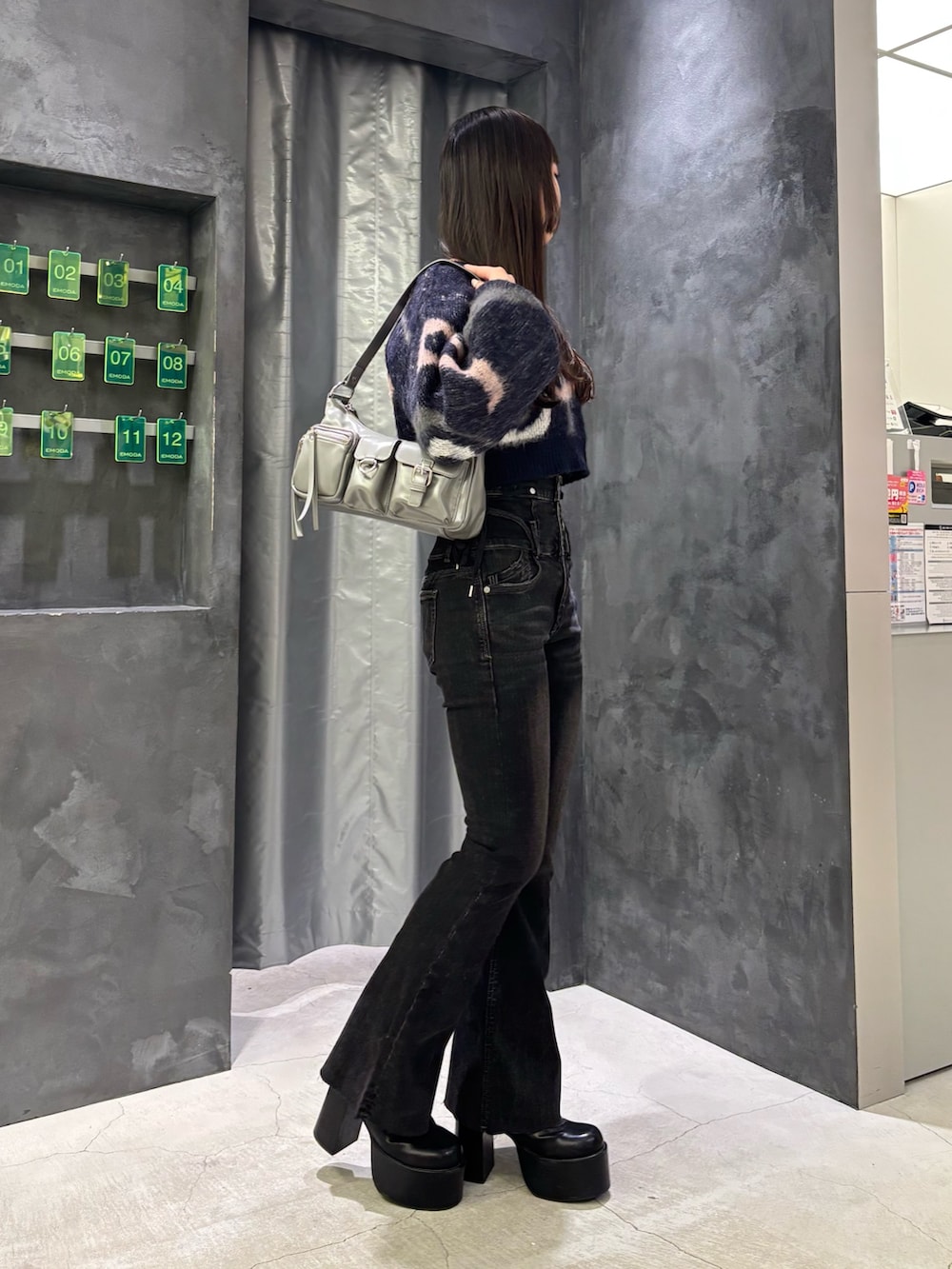 ブルー系のニット/セーター、グレー系のハンドバッグ、ブラック系のデニムパンツを着用したレディースの秋コーディネートの2枚目の写真